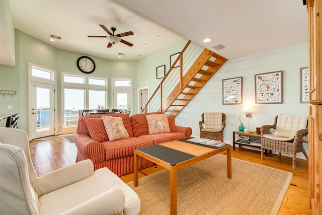 living room featuring ceiling fan, light hardwood / wood-style flooring, and a high ceiling