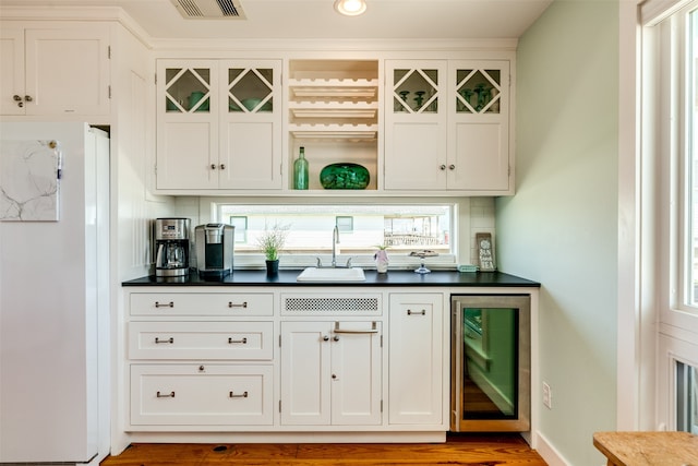 bar featuring wine cooler, white cabinetry, and sink