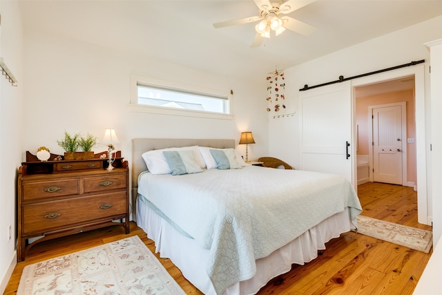 bedroom featuring a barn door, ceiling fan, and hardwood / wood-style flooring