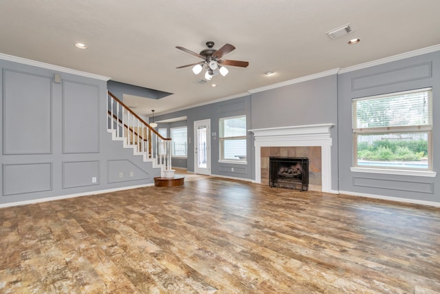 unfurnished living room with a tiled fireplace, ceiling fan, hardwood / wood-style floors, and ornamental molding