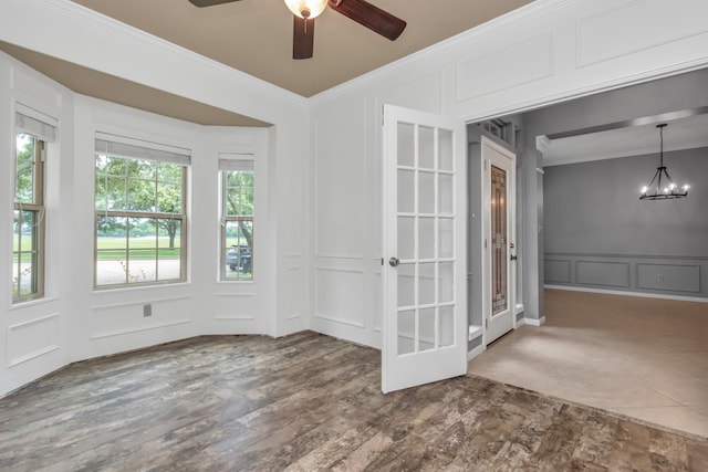 unfurnished room featuring wood-type flooring, ceiling fan with notable chandelier, and ornamental molding