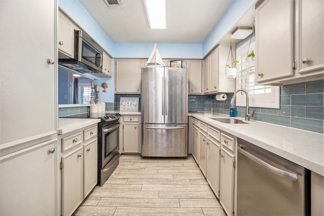 kitchen featuring decorative backsplash, sink, light hardwood / wood-style flooring, and appliances with stainless steel finishes