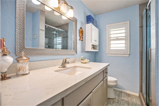 bathroom with hardwood / wood-style flooring, vanity, toilet, and a shower with shower door