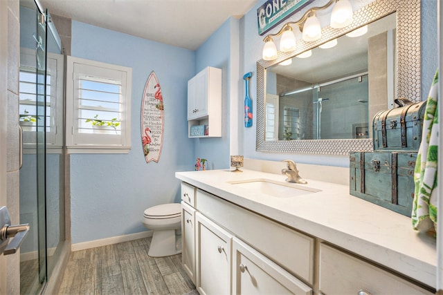 bathroom featuring hardwood / wood-style flooring, vanity, toilet, and a shower with door