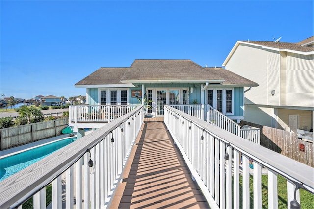 rear view of house featuring a fenced in pool and french doors