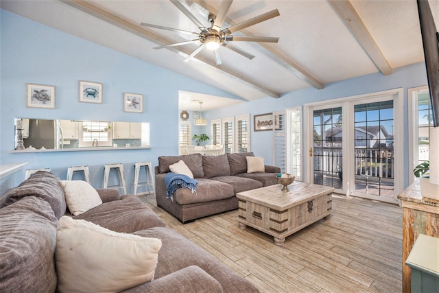 living room with vaulted ceiling with beams, sink, ceiling fan with notable chandelier, and light wood-type flooring