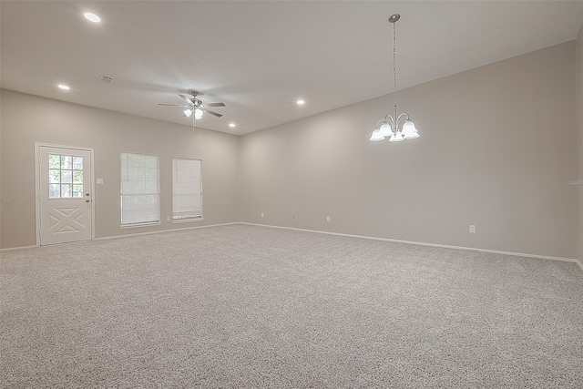 carpeted spare room featuring ceiling fan with notable chandelier