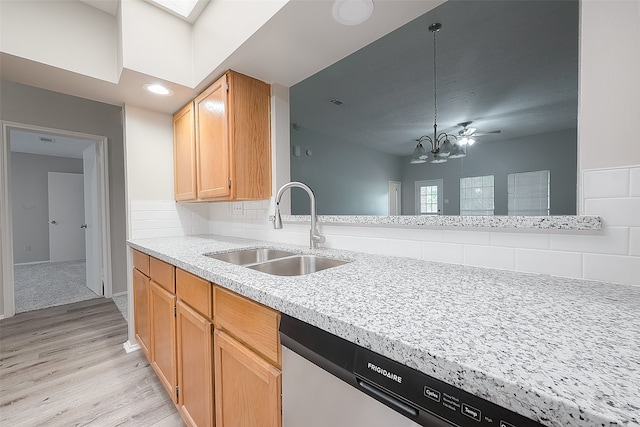 kitchen featuring a skylight, stainless steel dishwasher, sink, pendant lighting, and light hardwood / wood-style flooring