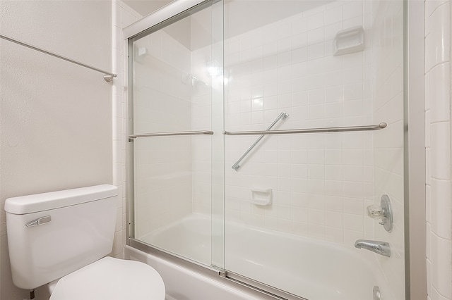 bathroom featuring enclosed tub / shower combo and toilet