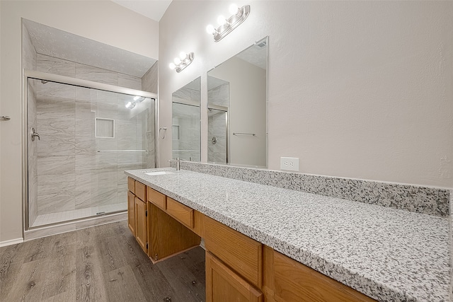 bathroom with hardwood / wood-style floors, vanity, and a shower with shower door