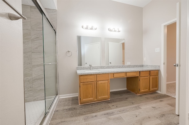 bathroom with wood-type flooring, vanity, and an enclosed shower