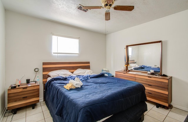 bedroom with ceiling fan, light tile patterned floors, and a textured ceiling