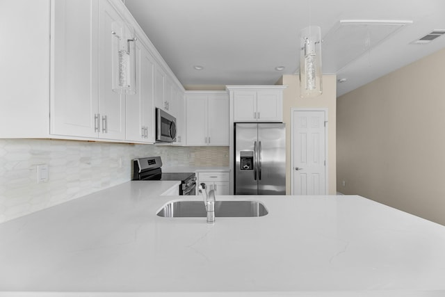 kitchen with white cabinets, sink, tasteful backsplash, decorative light fixtures, and stainless steel appliances