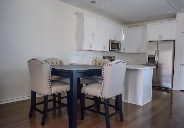 kitchen featuring white cabinets, decorative backsplash, stainless steel appliances, and dark wood-type flooring