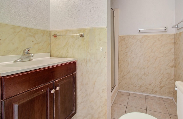 bathroom featuring tile patterned flooring, a textured ceiling, vanity, and toilet