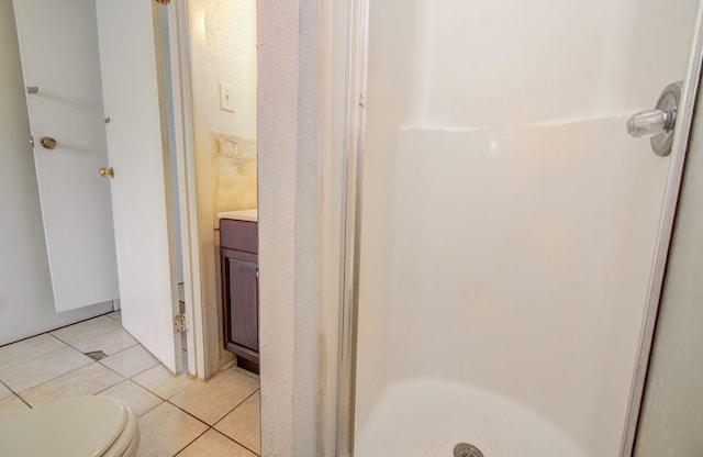 bathroom featuring toilet, vanity, tile patterned floors, and walk in shower