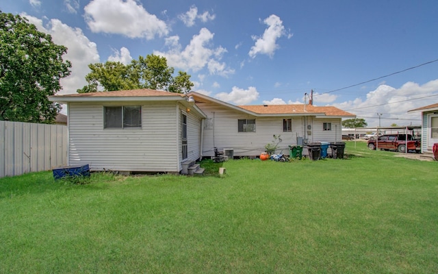 rear view of house featuring central AC and a lawn