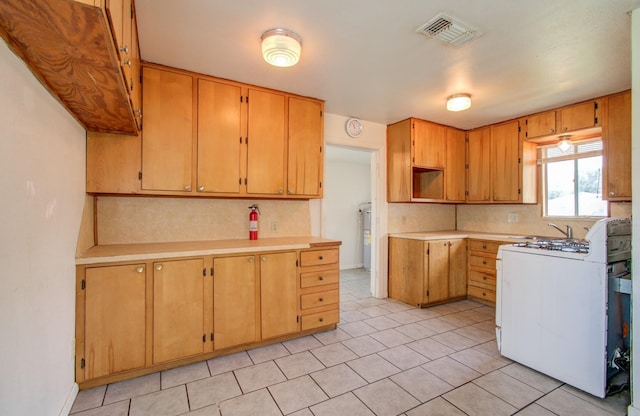 kitchen featuring washer / dryer, white gas range, backsplash, and water heater