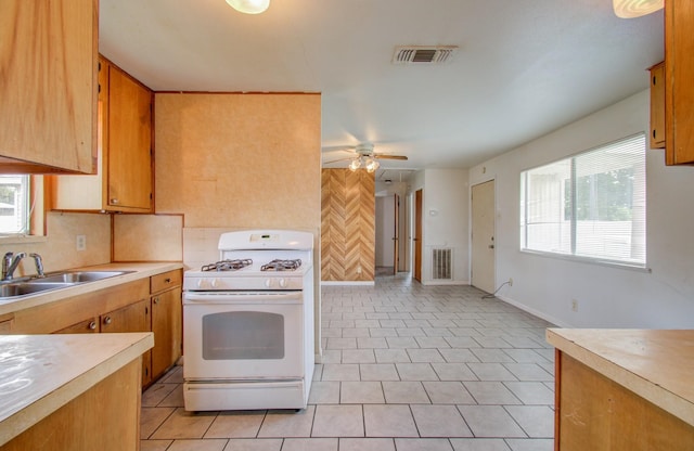 kitchen featuring ceiling fan, white gas range, sink, and light tile patterned floors