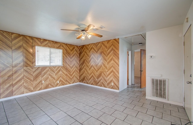 unfurnished room featuring ceiling fan and wood walls