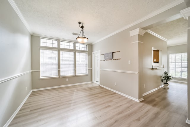 empty room with a textured ceiling, light wood-type flooring, and crown molding