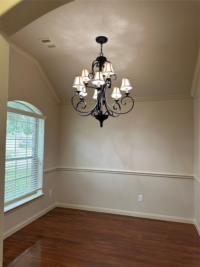 spare room featuring lofted ceiling, ornamental molding, dark hardwood / wood-style floors, and an inviting chandelier