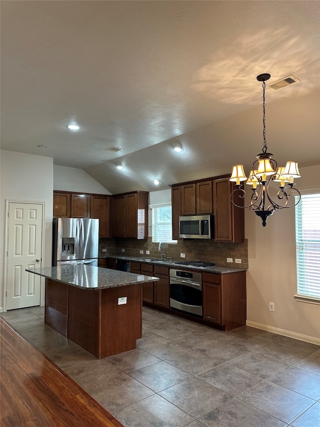 kitchen with a center island, hanging light fixtures, stainless steel appliances, hardwood / wood-style floors, and vaulted ceiling