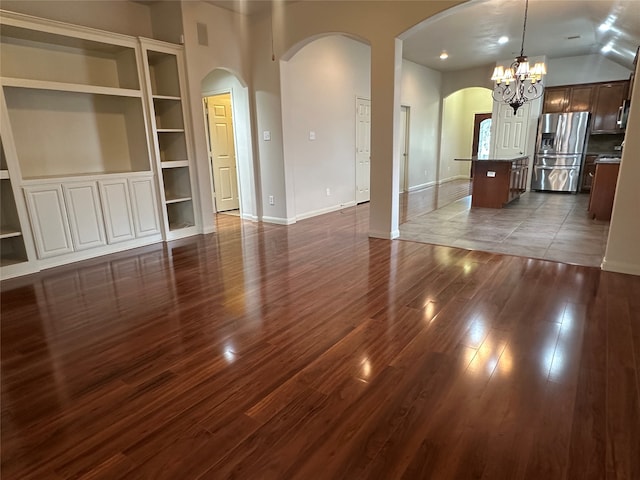 unfurnished living room with built in shelves, dark hardwood / wood-style flooring, and a chandelier