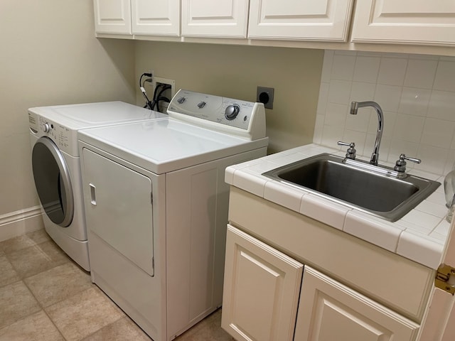 washroom with cabinets, light tile patterned floors, separate washer and dryer, and sink