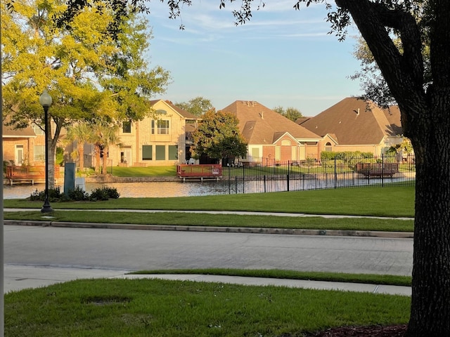 view of property's community with a water view and a lawn