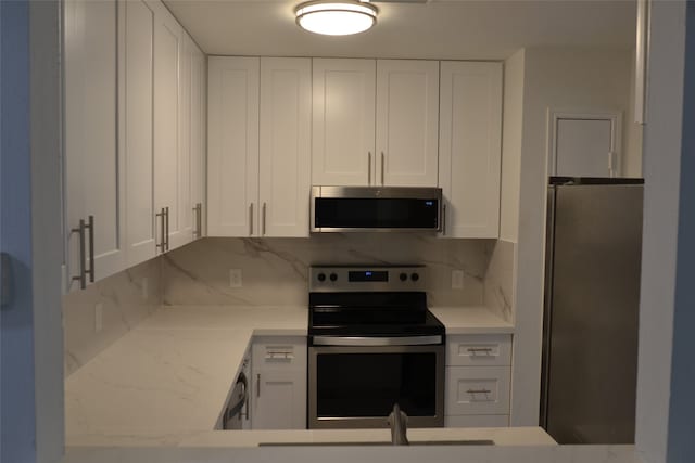 kitchen with white cabinetry, light stone counters, and appliances with stainless steel finishes