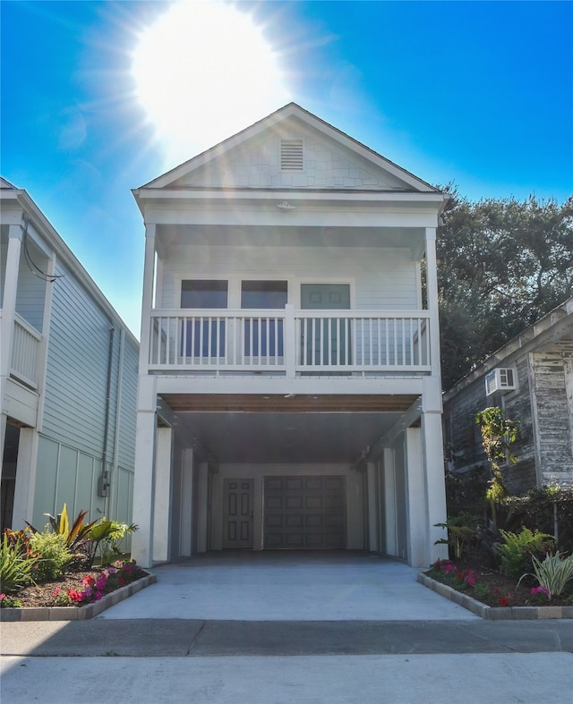 view of front facade with a carport, a balcony, and a wall mounted air conditioner