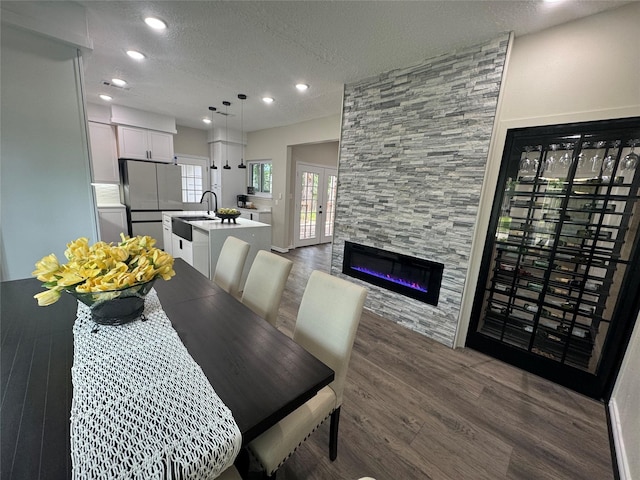 dining area featuring a tile fireplace, a textured ceiling, and dark hardwood / wood-style floors