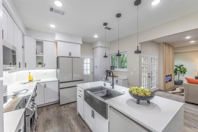 kitchen featuring white cabinets, a textured ceiling, appliances with stainless steel finishes, and hanging light fixtures