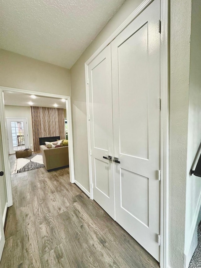 hallway with a textured ceiling and light wood-type flooring