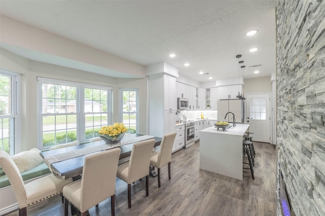 dining area featuring sink, a textured ceiling, and hardwood / wood-style flooring