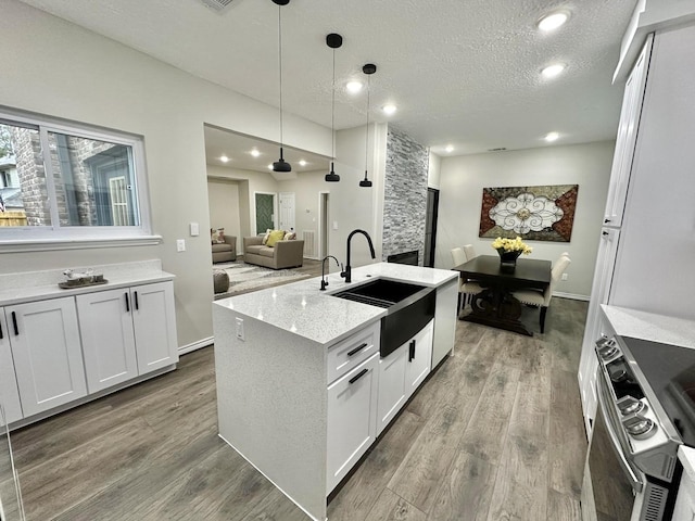 kitchen featuring sink, white cabinetry, decorative light fixtures, and light stone counters