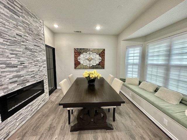 dining space featuring a tile fireplace, a textured ceiling, and hardwood / wood-style floors