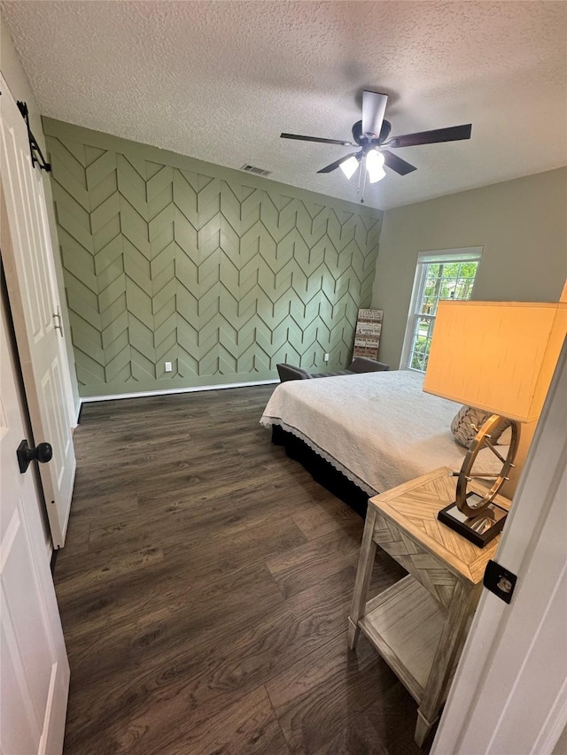 bedroom featuring ceiling fan, dark wood-type flooring, and a textured ceiling