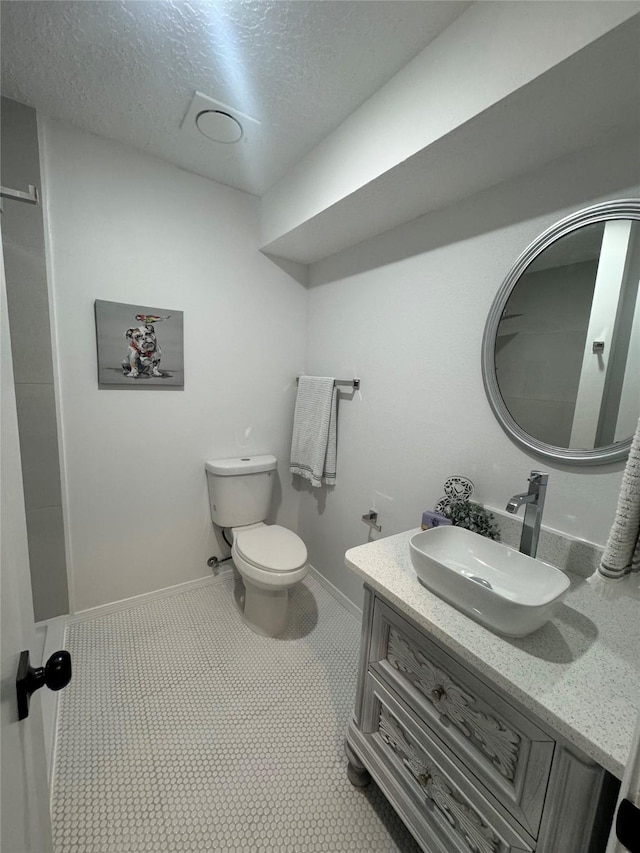 bathroom featuring a textured ceiling, tile patterned floors, vanity, and toilet