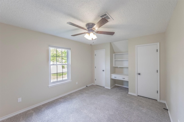 unfurnished bedroom featuring light colored carpet, ceiling fan, and a textured ceiling