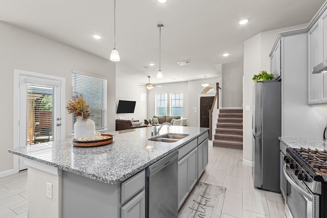 kitchen featuring a healthy amount of sunlight, sink, stainless steel appliances, and a kitchen island with sink