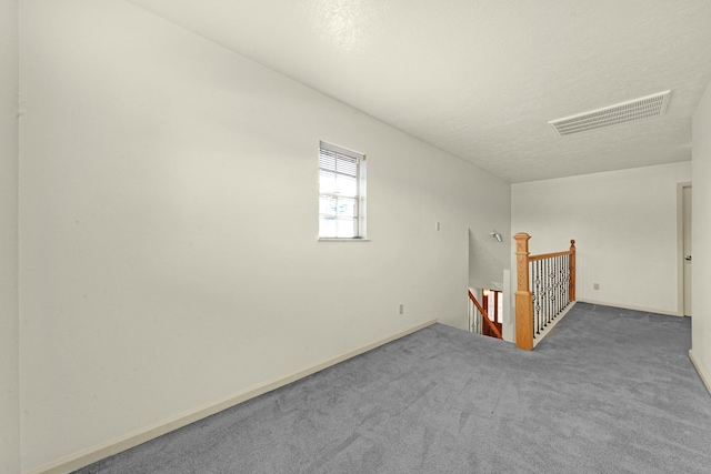 bonus room featuring dark colored carpet and a textured ceiling