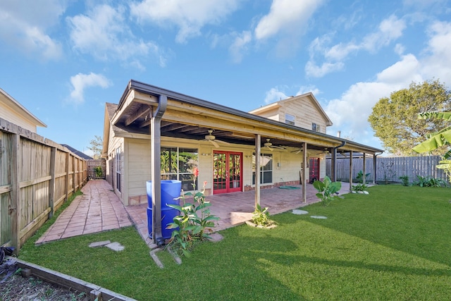 rear view of house with ceiling fan, a patio area, and a lawn