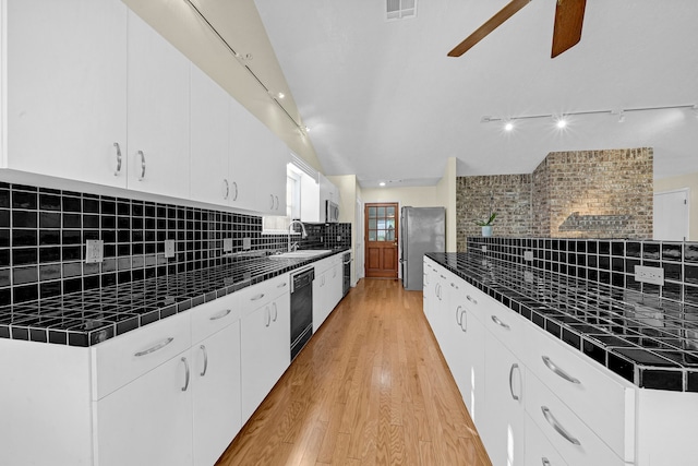 kitchen featuring sink, light hardwood / wood-style flooring, decorative backsplash, appliances with stainless steel finishes, and white cabinetry