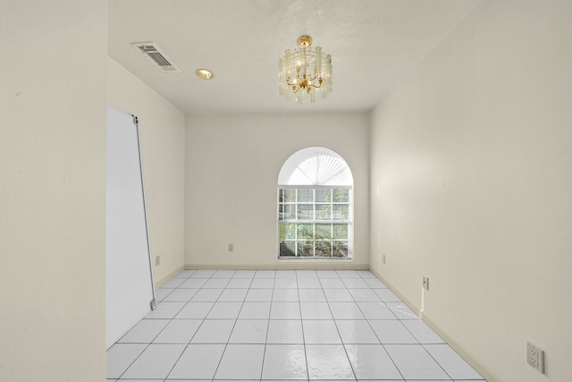 empty room with light tile patterned flooring and a notable chandelier