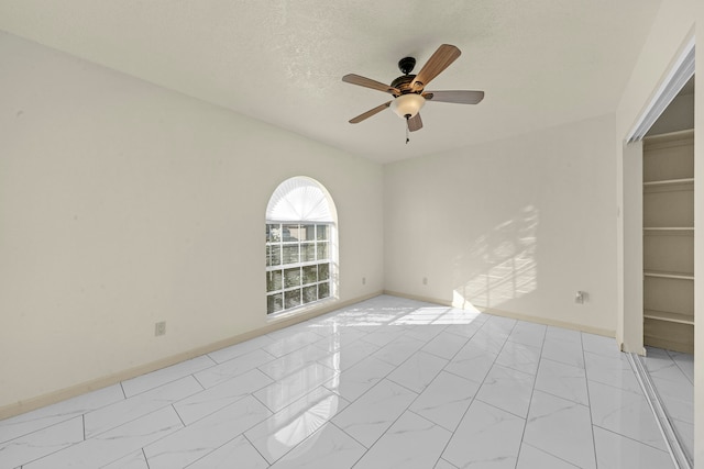 empty room with ceiling fan and a textured ceiling