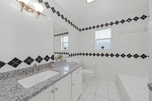 bathroom featuring vanity, tile patterned flooring, toilet, a tub to relax in, and tile walls