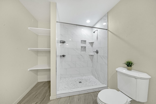 bathroom with hardwood / wood-style floors, toilet, and tiled shower