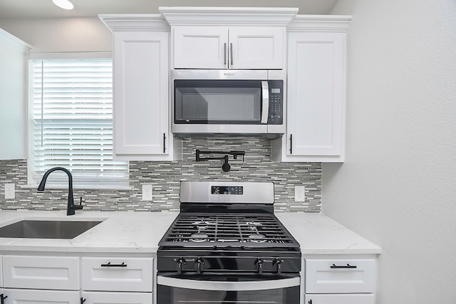 kitchen with backsplash, white cabinetry, sink, and stainless steel appliances